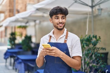 Canvas Print - Young arab man waiter using smartphone working at restaurant