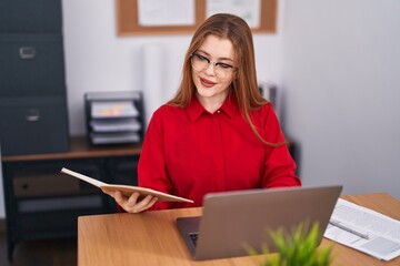 Wall Mural - Young redhead woman business worker using laptop reading notebook at office