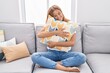 © Krakenimages.com - Young blonde girl hugging cushion sitting on sofa at home