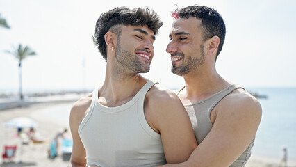 Wall Mural - Two men couple smiling confident hugging each other at seaside