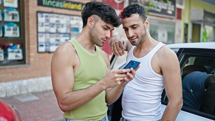 Wall Mural - Two men couple using smartphone standing by car at street