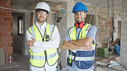 Canvas Print - Two men builders smiling confident standing with arms crossed gesture at construction site