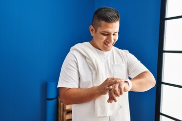 Poster - Young latin man smiling confident looking stopwatch at sport center