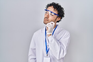 Wall Mural - Hispanic man working at scientist laboratory thinking concentrated about doubt with finger on chin and looking up wondering