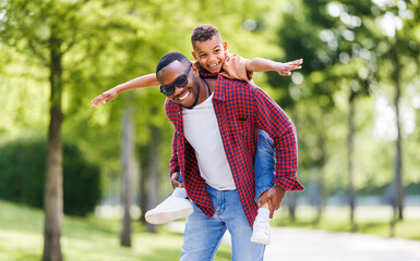 Happy ethnic family father and son have fun on  walk in summer park