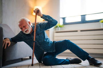 senior man falling on the ground with walker in living room at home. elderly older mature male havin