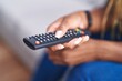 © Krakenimages.com - African american woman holding tv remote control sitting on sofa at home