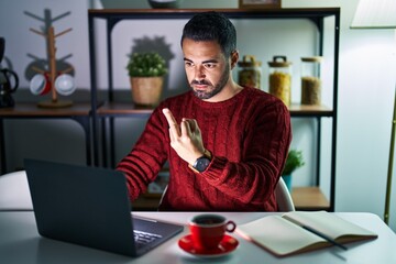 Canvas Print - Young hispanic man with beard using computer laptop at night at home showing middle finger, impolite and rude fuck off expression