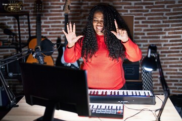 Poster - Plus size hispanic woman playing piano at music studio showing and pointing up with fingers number seven while smiling confident and happy.