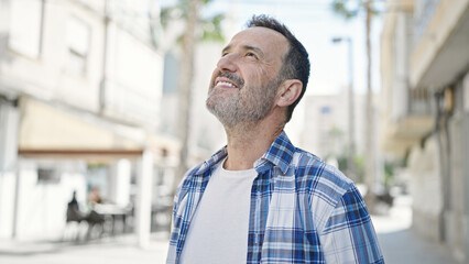 Wall Mural - Middle age man smiling confident looking to the sky at street