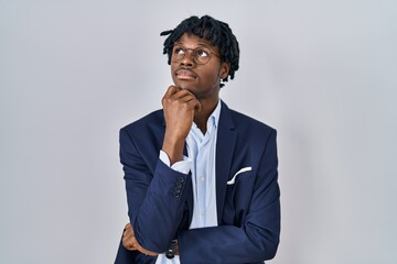 Sticker - Young african man with dreadlocks wearing business jacket over white background with hand on chin thinking about question, pensive expression. smiling with thoughtful face. doubt concept.