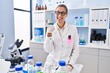 © Krakenimages.com - Young woman working at scientist laboratory pointing thumb up to the side smiling happy with open mouth