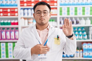 Poster - Chinese young man working at pharmacy drugstore swearing with hand on chest and open palm, making a loyalty promise oath