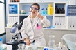 © Krakenimages.com - Hispanic girl with down syndrome working at scientist laboratory pointing with hand finger to face and nose, smiling cheerful. beauty concept