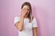 Blonde caucasian woman standing over pink background yawning tired covering half face, eye and mouth with hand. face hurts in pain.