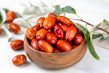 Wall Mural - Fresh raw silverberry fruits in bowl with bunch of silverberry tree, oleaster or russian olive ( Elaeagnus )