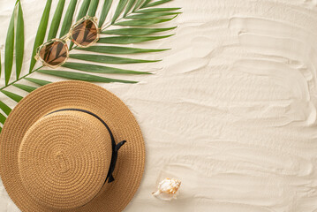 From above, the essence of summer lounging. Top view of stylish sunglasses, sunhat, seashell, and palm leaves on the sandy shore. An empty space provides room for custom text or promotional purposes