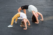 © Михаил Решетников - A little girl and her mom do a bridge exercise at the outdoor sports ground.