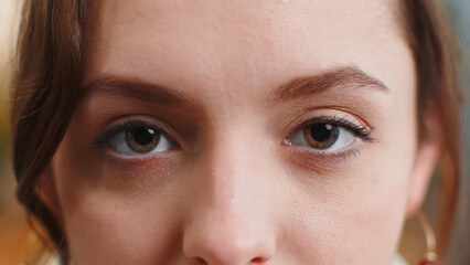 Extreme close-up macro portrait of smiling young adult woman face. Brunette girl eyes, looking at camera. Green brown eyes of lady. Portrait of teenager positive female opening wide her closed eyes