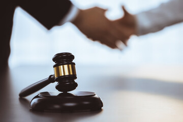 Wall Mural - Focus gavel symbolize justice on blur background of lawyer colleagues handshake after successful legal deal for lawsuit to advocate resolves dispute in court ensuring trustworthy partner. Equilibrium