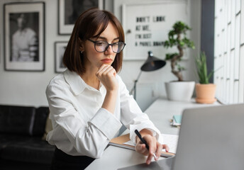 Women in business. Focused young lady manager in formal outfit, CEO sitting in front of laptop, working in office