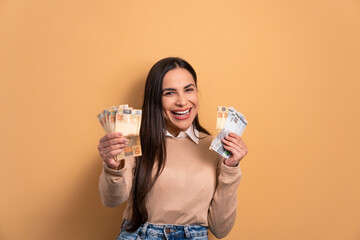 excited young woman with brazil banknotes currency in beige colors. economy, payment, successful concept. 