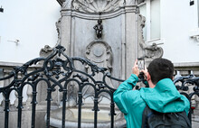 Bruxelles, Belgium: Tourist Taking Photo Of Maneken Pis, Symbol Of Brussels. Famous Landmark, Bronze Fountain Sculpture In City Centre. 
