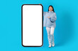 © Prostock-studio - Happy young chinese lady pointing at huge phone with mockup