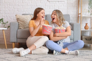 Wall Mural - Young sisters eating popcorn at home