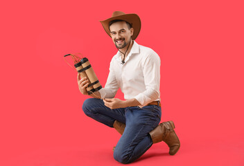 Wall Mural - Handsome cowboy with explosive on red background