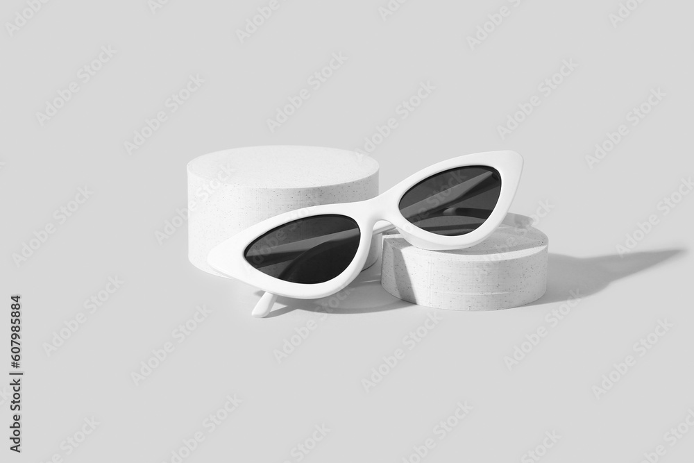 Podiums with stylish sunglasses on white background