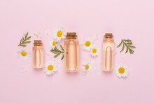 Bottles With Chamomile Essential Oil And Flowers On Color Background, Top View