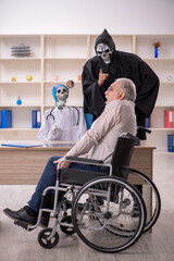 Wall Mural - Old patient in wheel-chair visiting two devil doctors