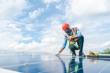 african american engineer maintaining solar cell panels on factory building rooftop. technician work