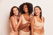 © South House Studio - Photo portrait of black lovely female model with two her girl friends in nude-colored underwear standing on white studio background hugging and smile, spending time together concept, copy space