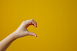 Young adult woman forming shape of half of heart with her fingers