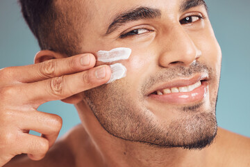 Poster - Portrait, beauty and skin cream with a man in studio on a gray background to apply antiaging facial treatment. Face, skincare and lotion with a young person indoor for wellness or aesthetic self care