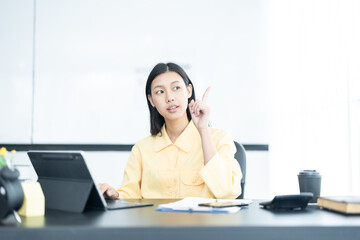 Portrait of pretty cheerful girl smiling while working on laptop in office