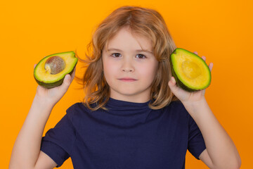 Wall Mural - Avocado. Kid hold red avocado in studio. Studio portrait of cute child with avocado isolated on yellow background, copy space.