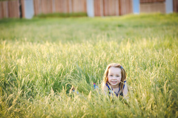 Wall Mural - Lovely caucasian girl with long hair lying in long grass at the park with big smile