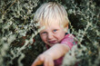 © Caseyjadew - Cute blonde toddler boy with blue eyes hiding in bush. Child playing in nature with big smile