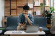 © Nuttapong punna - Young business man working at office with laptop, tablet and taking notes on the paper. on sofa in liveing room at home..