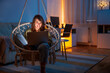 Woman using laptop computer while relaxing at home late at night