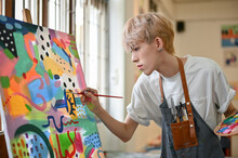 A Talented Young Asian Queer Artist Focuses On Painting His Picture On A Canvas Easel