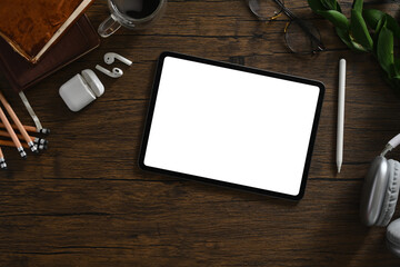 Digital tablet, headphone and stationery on wooden table. Blank screen for your advertising text message