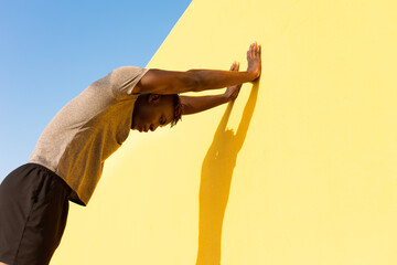 Young man doing stretching exercise outside. African man training outside..