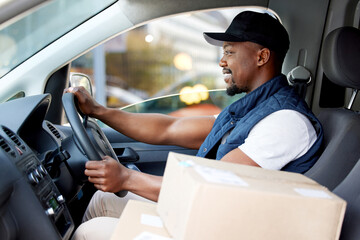 Delivery man, transport and man driving with a smile for shipping or courier service. Happy black person or driver with cardboard box, package or parcel in a van, cargo vehicle or transportation