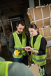© LIGHTFIELD STUDIOS - Male worker in safety vest and gloves talking to young colleague using digital tablet near waste paper at background in garbage sorting center, waste sorting and recycling concept