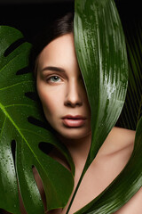 Beauty Portrait of brunette girl in palm leaves. Beautiful young woman with Make-up