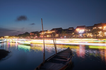 Wall Mural - Light trails of boats with traditional lanterns on the motion. Night scene of water canal and waterfront in ancient city Hoi An in Vietnam..